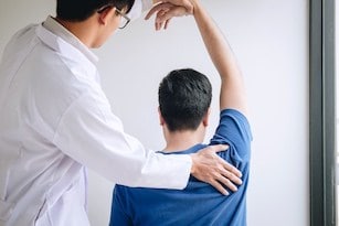 Car Accident Doctor helping man's arm after car accident injury